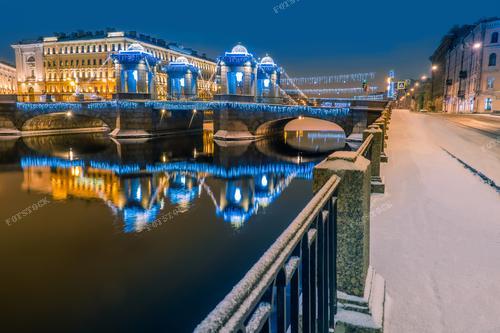 Фотография захватывает великолепие зимнего Санкт-Петербурга, где река Фонтанка, мосты и улицы украшены рождественской иллюминацией. Снимок погружает в атмосферу городского центра, где волшебство Рождества преображает улицы в яркий и уютный праздничный ландшафт.

Эта фотография — не только красивый отражение зимней красоты Санкт-Петербурга, но и эстетическое сочетание природы и архитектурного наследия. Покупка этой фотографии — ваша возможность внести атмосферу праздника и волшебства в ваш дом.

Украшенные мосты Фонтанки в сочетании с рождественской иллюминацией создают неповторимый вид. Это изображение станет отличным подарком для любителей города и тех, кто ценит атмосферу новогодних и рождественских праздников в историческом центре Петербурга.

Эта фотография также подходит для использования в новогодних открытках, календарях или декоре вашего дома, чтобы создать праздничное настроение и поделиться красотой Рождественских каникул.